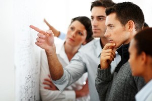 Group of business associates looking and pointing at a chart put up on the wall